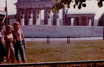 1984, devant la porte de Brandebourg avec mes deux soeurs de Californie. Je suis à gauche. Derrière, une affiche dit : Attention, vous quittez Berlin-Ouest.